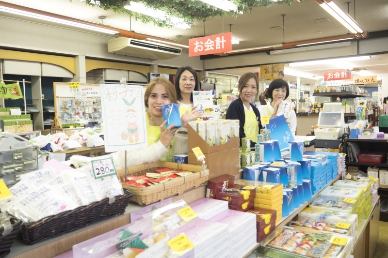 Four women smiling with products in their hands at the sales floor